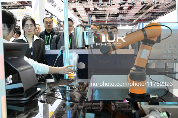 Visitors watch a ''bartending robot'' perform in front of the Siemens stand in the Technical Equipment Exhibition area of the 7th China Inte...