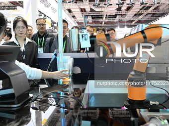 Visitors watch a ''bartending robot'' perform in front of the Siemens stand in the Technical Equipment Exhibition area of the 7th China Inte...