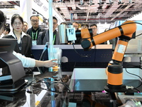 Visitors watch a ''bartending robot'' perform in front of the Siemens stand in the Technical Equipment Exhibition area of the 7th China Inte...