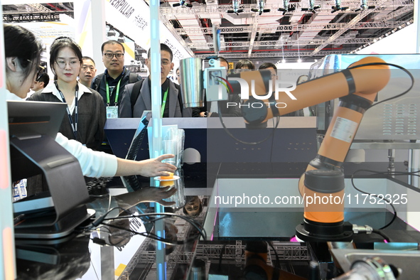 Visitors watch a ''bartending robot'' perform in front of the Siemens stand in the Technical Equipment Exhibition area of the 7th China Inte...