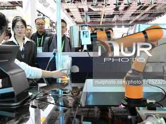 Visitors watch a ''bartending robot'' perform in front of the Siemens stand in the Technical Equipment Exhibition area of the 7th China Inte...