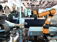 Visitors watch a ''bartending robot'' perform in front of the Siemens stand in the Technical Equipment Exhibition area of the 7th China Inte...