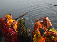 Hindu women worship the Sun god in the early morning during the religious festival of Chhath Puja at a pond in Kolkata, India, on November 8...