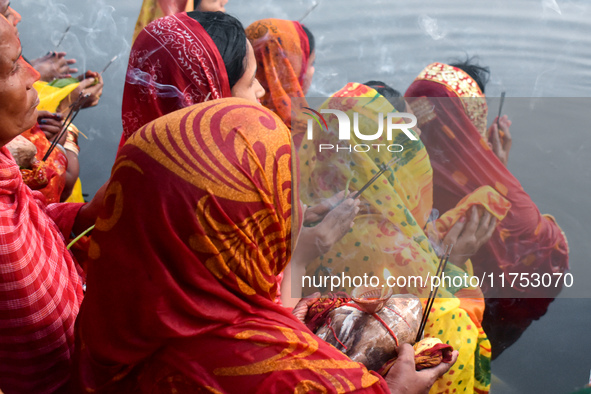 Hindu women worship the Sun god in the early morning during the religious festival of Chhath Puja at a pond in Kolkata, India, on November 8...