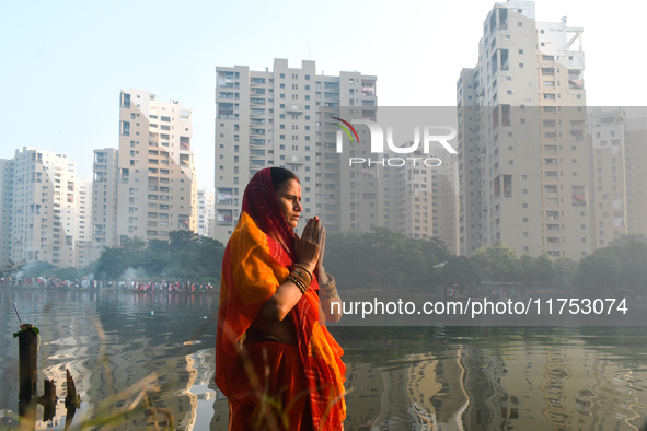 A Hindu woman worships the Sun god in the early morning during the religious festival of Chhath Puja at a pond in Kolkata, India, on Novembe...