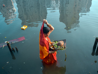 A Hindu woman worships the Sun god in the early morning during the religious festival of Chhath Puja at a pond in Kolkata, India, on Novembe...