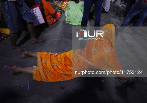 A Hindu devotee lies on the road as she worships the Sun god at dawn on the banks of the river Ganges during the last day of the Hindu relig...