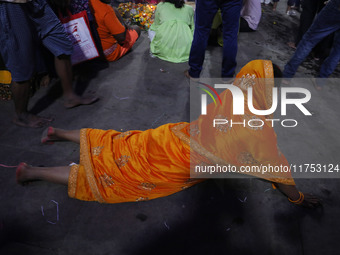 A Hindu devotee lies on the road as she worships the Sun god at dawn on the banks of the river Ganges during the last day of the Hindu relig...