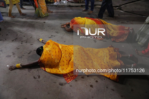 A Hindu devotee lies on the road as she worships the Sun god at dawn on the banks of the river Ganges during the last day of the Hindu relig...