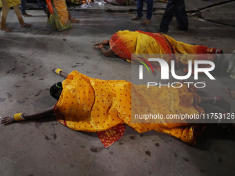 A Hindu devotee lies on the road as she worships the Sun god at dawn on the banks of the river Ganges during the last day of the Hindu relig...