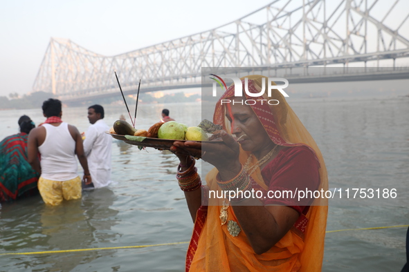 A Hindu devotee holds offerings as she stands in the water of the river Ganges during the early morning in front of the iconic Howrah Bridge...