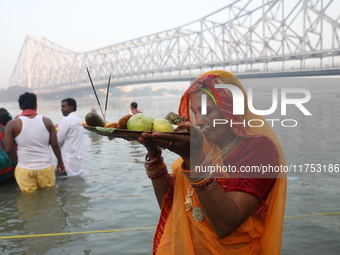 A Hindu devotee holds offerings as she stands in the water of the river Ganges during the early morning in front of the iconic Howrah Bridge...