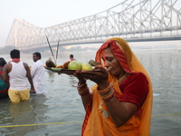 A Hindu devotee holds offerings as she stands in the water of the river Ganges during the early morning in front of the iconic Howrah Bridge...