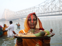 A Hindu devotee holds offerings as she stands in the water of the river Ganges during the early morning in front of the iconic Howrah Bridge...