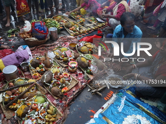 Hindu devotees hold offerings during the early morning as they offer prayers to the Sun god on the banks of the river Ganges during the last...