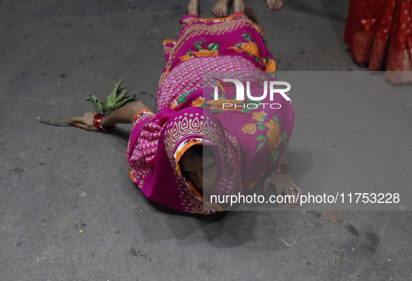 A Hindu devotee lies on the road as she worships the Sun god at dawn on the banks of the river Ganges during the last day of the Hindu relig...