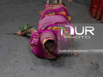 A Hindu devotee lies on the road as she worships the Sun god at dawn on the banks of the river Ganges during the last day of the Hindu relig...