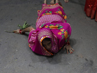 A Hindu devotee lies on the road as she worships the Sun god at dawn on the banks of the river Ganges during the last day of the Hindu relig...