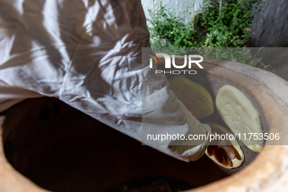 A woman bakes fresh bread on a small stand on a street in Kairouan, central Tunisia on October 31, 2024. Tunisia is well known for its natur...