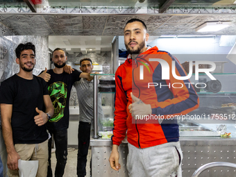 Young men pose to be photographed in a small restaurant in Tunis, central Tunisia on November 2, 2024. Tunisia is well known for its natural...