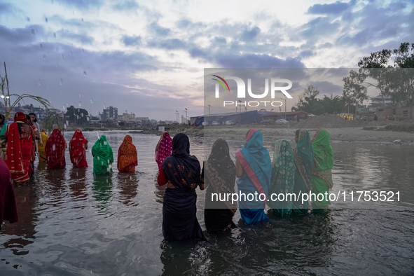 Hindu devotees perform rituals and offer prayers to the rising Sun God on the banks of the Bagmati River during the 'Chhath Puja' festival i...