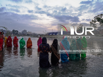 Hindu devotees perform rituals and offer prayers to the rising Sun God on the banks of the Bagmati River during the 'Chhath Puja' festival i...