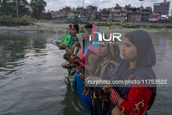 Hindu devotees perform rituals and offer prayers to the rising Sun God on the banks of the Bagmati River during the 'Chhath Puja' festival i...