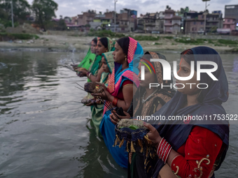 Hindu devotees perform rituals and offer prayers to the rising Sun God on the banks of the Bagmati River during the 'Chhath Puja' festival i...