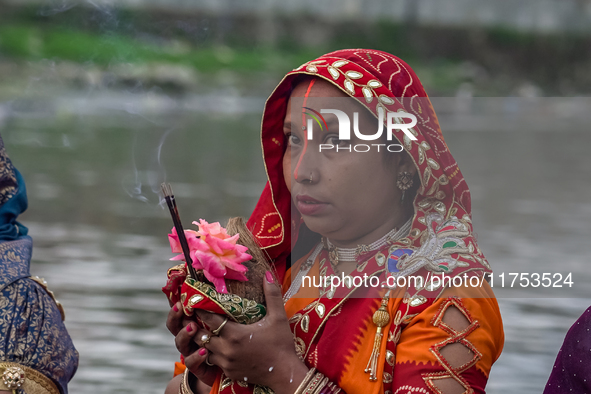 Hindu devotees perform rituals and offer prayers to the rising Sun God on the banks of the Bagmati River during the 'Chhath Puja' festival i...