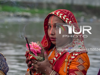 Hindu devotees perform rituals and offer prayers to the rising Sun God on the banks of the Bagmati River during the 'Chhath Puja' festival i...