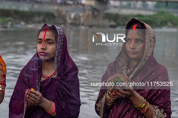 Hindu devotees perform rituals and offer prayers to the rising Sun God on the banks of the Bagmati River during the 'Chhath Puja' festival i...