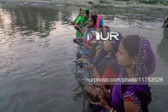 Hindu devotees perform rituals and offer prayers to the rising Sun God on the banks of the Bagmati River during the 'Chhath Puja' festival i...