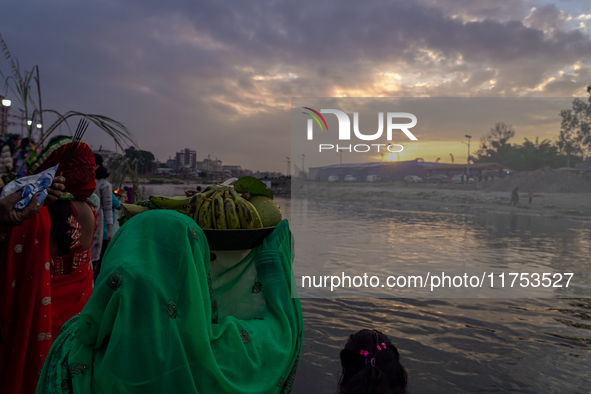 Hindu devotees perform rituals and offer prayers to the rising Sun God on the banks of the Bagmati River during the 'Chhath Puja' festival i...