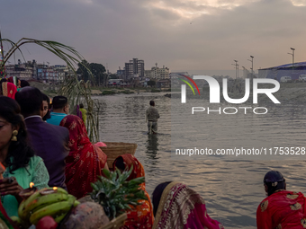 Hindu devotees perform rituals and offer prayers to the rising Sun God on the banks of the Bagmati River during the 'Chhath Puja' festival i...