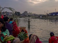 Hindu devotees perform rituals and offer prayers to the rising Sun God on the banks of the Bagmati River during the 'Chhath Puja' festival i...