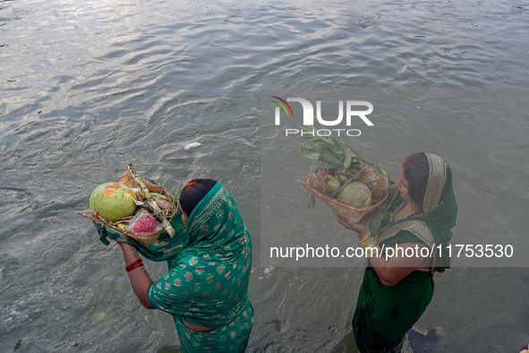 Hindu devotees perform rituals and offer prayers to the rising Sun God on the banks of the Bagmati River during the 'Chhath Puja' festival i...