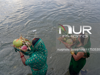 Hindu devotees perform rituals and offer prayers to the rising Sun God on the banks of the Bagmati River during the 'Chhath Puja' festival i...