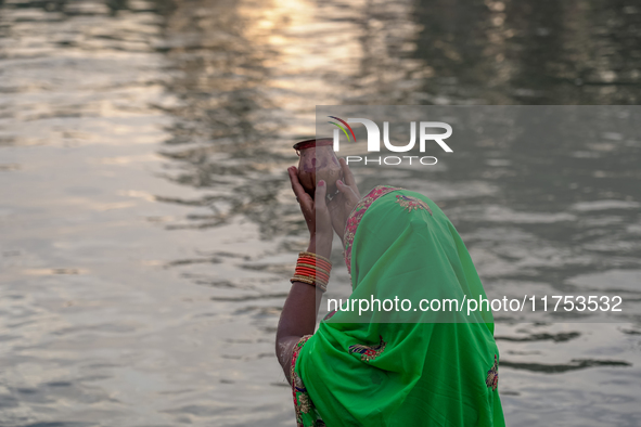 Hindu devotees perform rituals and offer prayers to the rising Sun God on the banks of the Bagmati River during the 'Chhath Puja' festival i...