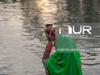 Hindu devotees perform rituals and offer prayers to the rising Sun God on the banks of the Bagmati River during the 'Chhath Puja' festival i...