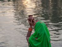 Hindu devotees perform rituals and offer prayers to the rising Sun God on the banks of the Bagmati River during the 'Chhath Puja' festival i...