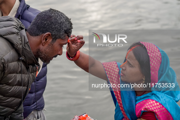 Hindu devotees apply tika after the rituals and offer prayers to the rising Sun God on the banks of the Bagmati River during the 'Chhath Puj...