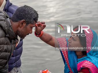 Hindu devotees apply tika after the rituals and offer prayers to the rising Sun God on the banks of the Bagmati River during the 'Chhath Puj...