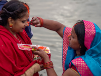 Hindu devotees apply tika after the rituals and offer prayers to the rising Sun God on the banks of the Bagmati River during the 'Chhath Puj...