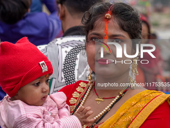 Hindu devotees perform rituals and offer prayers to the rising Sun God on the banks of the Bagmati River during the 'Chhath Puja' festival i...