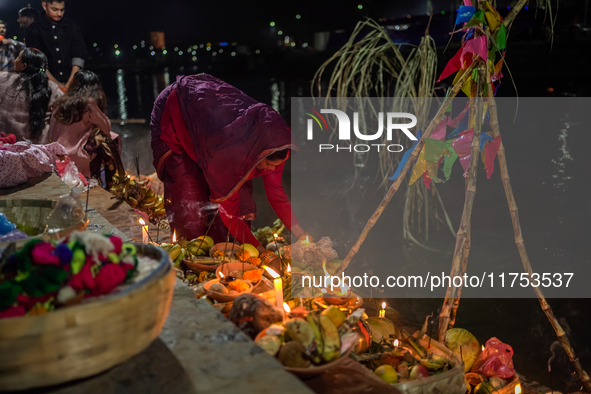 A Hindu devotee lights traditional oil lamps as she offers prayers to the sun during the Chhath Puja festival on the banks of the Bagmati Ri...