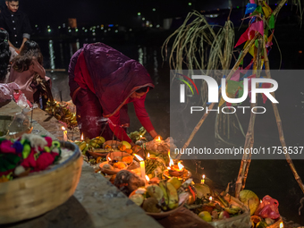 A Hindu devotee lights traditional oil lamps as she offers prayers to the sun during the Chhath Puja festival on the banks of the Bagmati Ri...