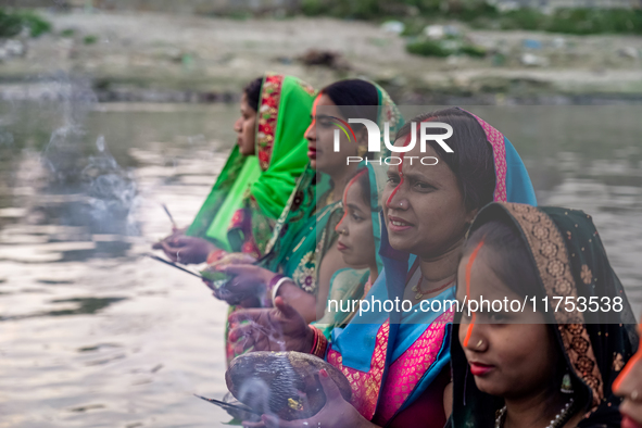 Hindu devotees perform rituals and offer prayers to the rising Sun God on the banks of the Bagmati River during the 'Chhath Puja' festival i...