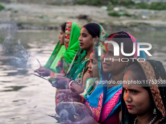 Hindu devotees perform rituals and offer prayers to the rising Sun God on the banks of the Bagmati River during the 'Chhath Puja' festival i...