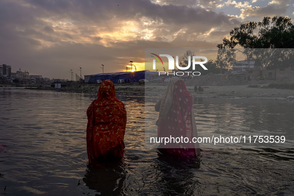 Hindu devotees perform rituals and offer prayers to the rising Sun God on the banks of the Bagmati River during the 'Chhath Puja' festival i...