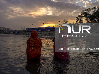 Hindu devotees perform rituals and offer prayers to the rising Sun God on the banks of the Bagmati River during the 'Chhath Puja' festival i...